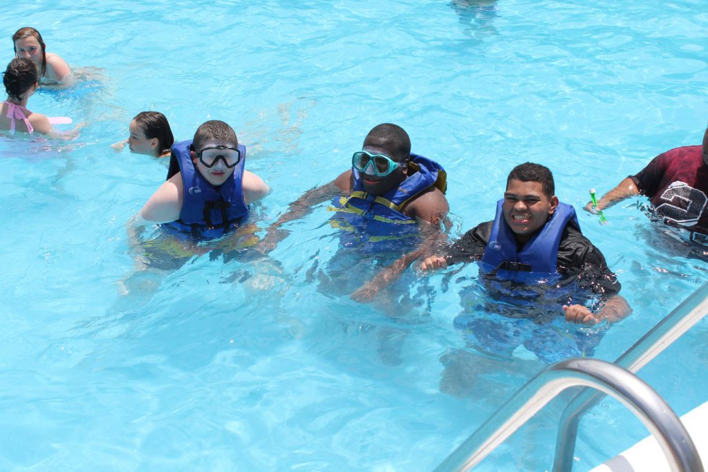 three boys wearing life jackets and swim masks in pool