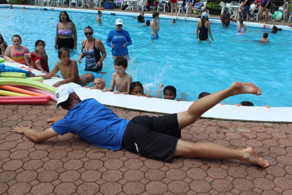 man showing students swim kicks by the pool