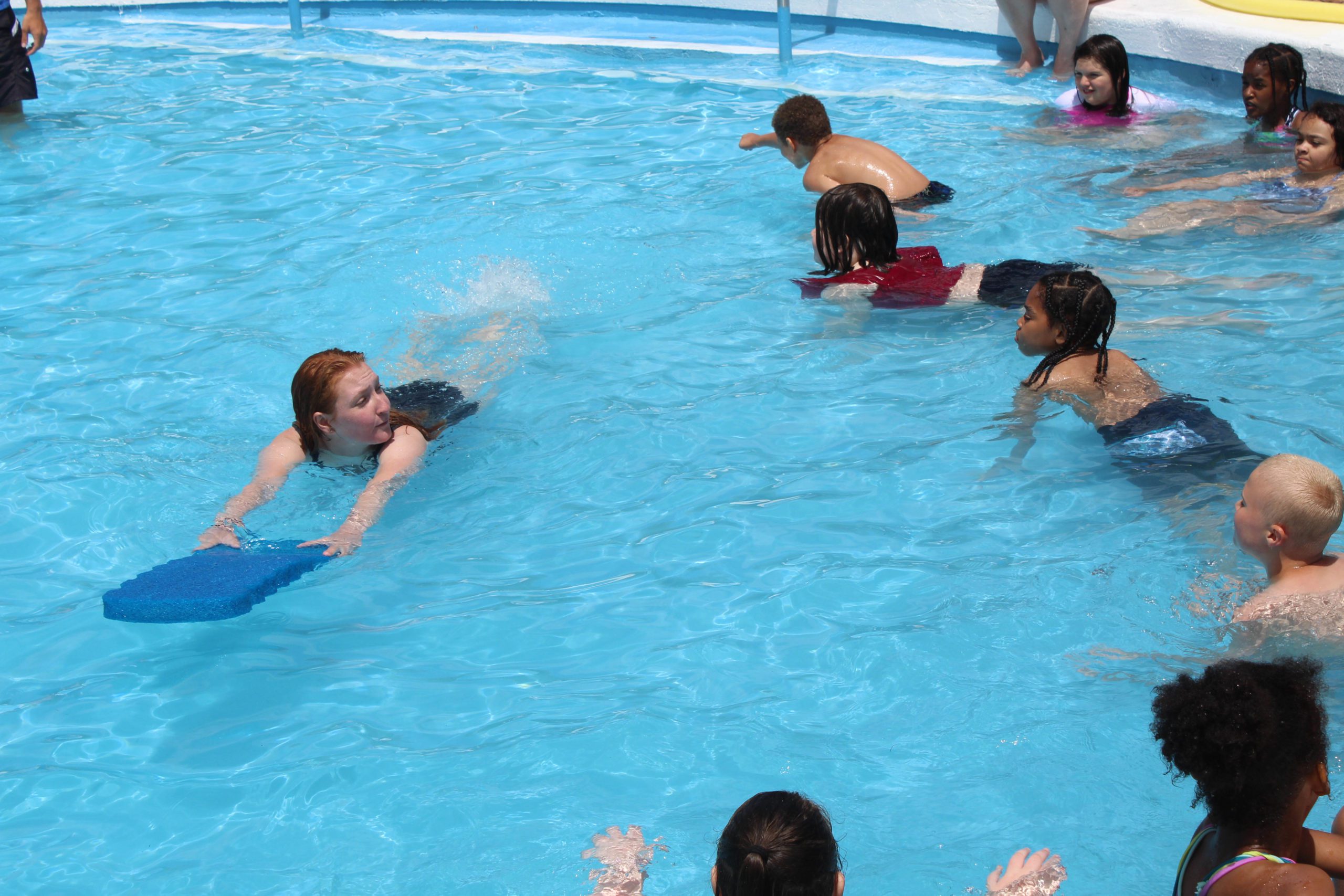 teacher showing students how to swim with pool float