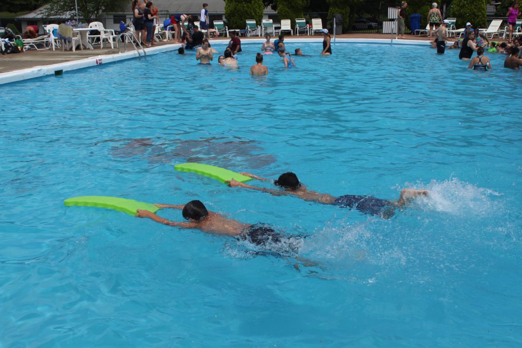 two boys pushing swim floats in pool
