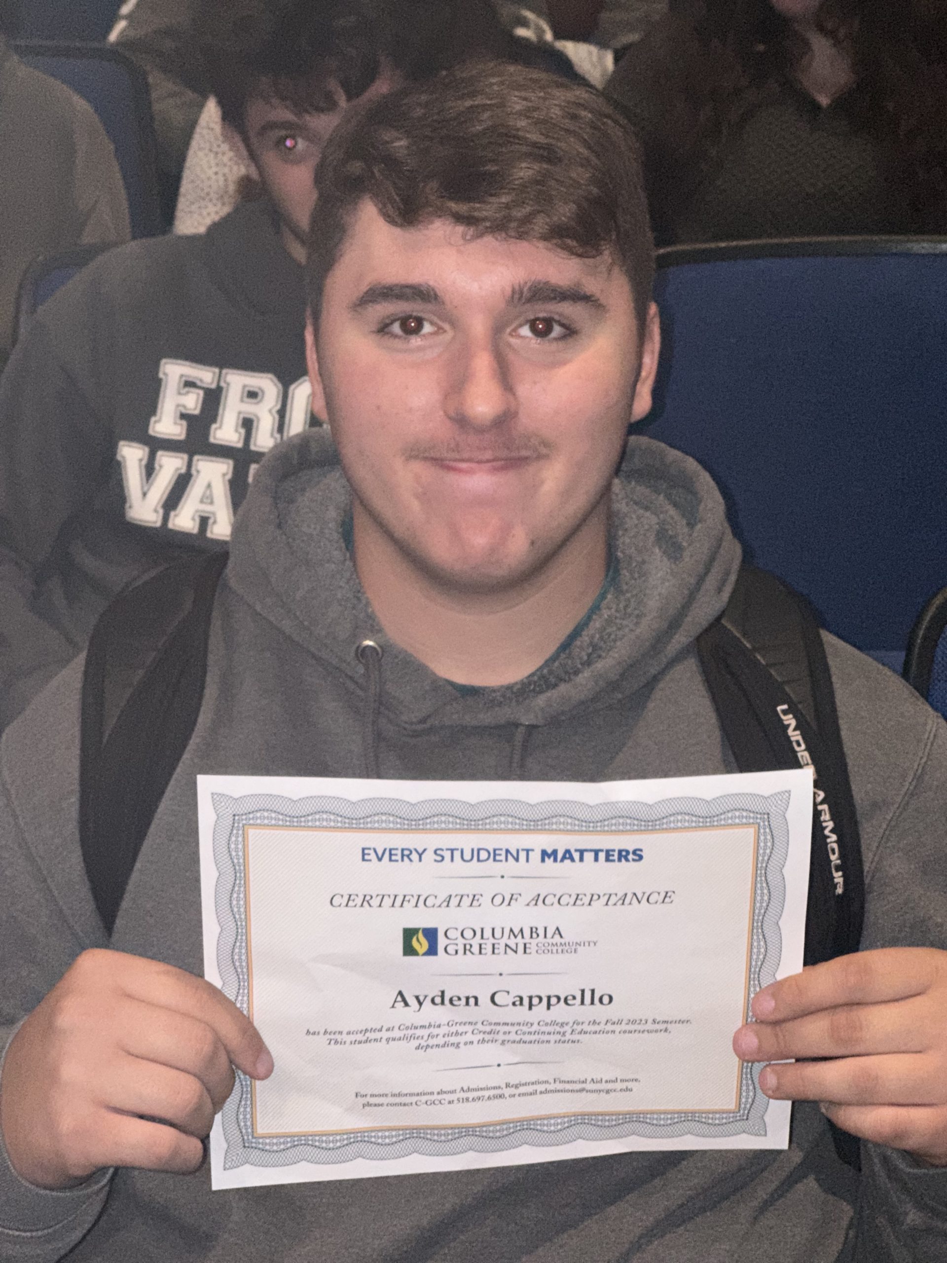young man holding instant admissions certificate