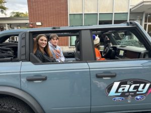 students ride in vehicle ion parade