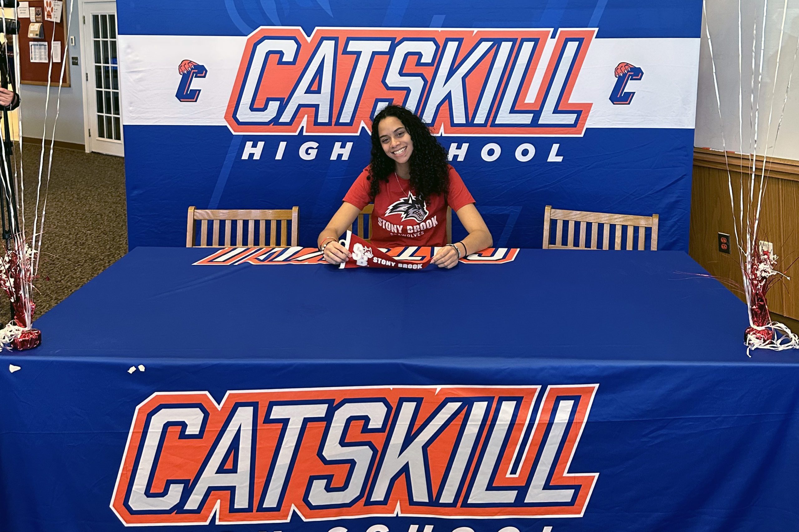 Janay Brantley signing letter of intent at table emblazoned with Catskill logo.