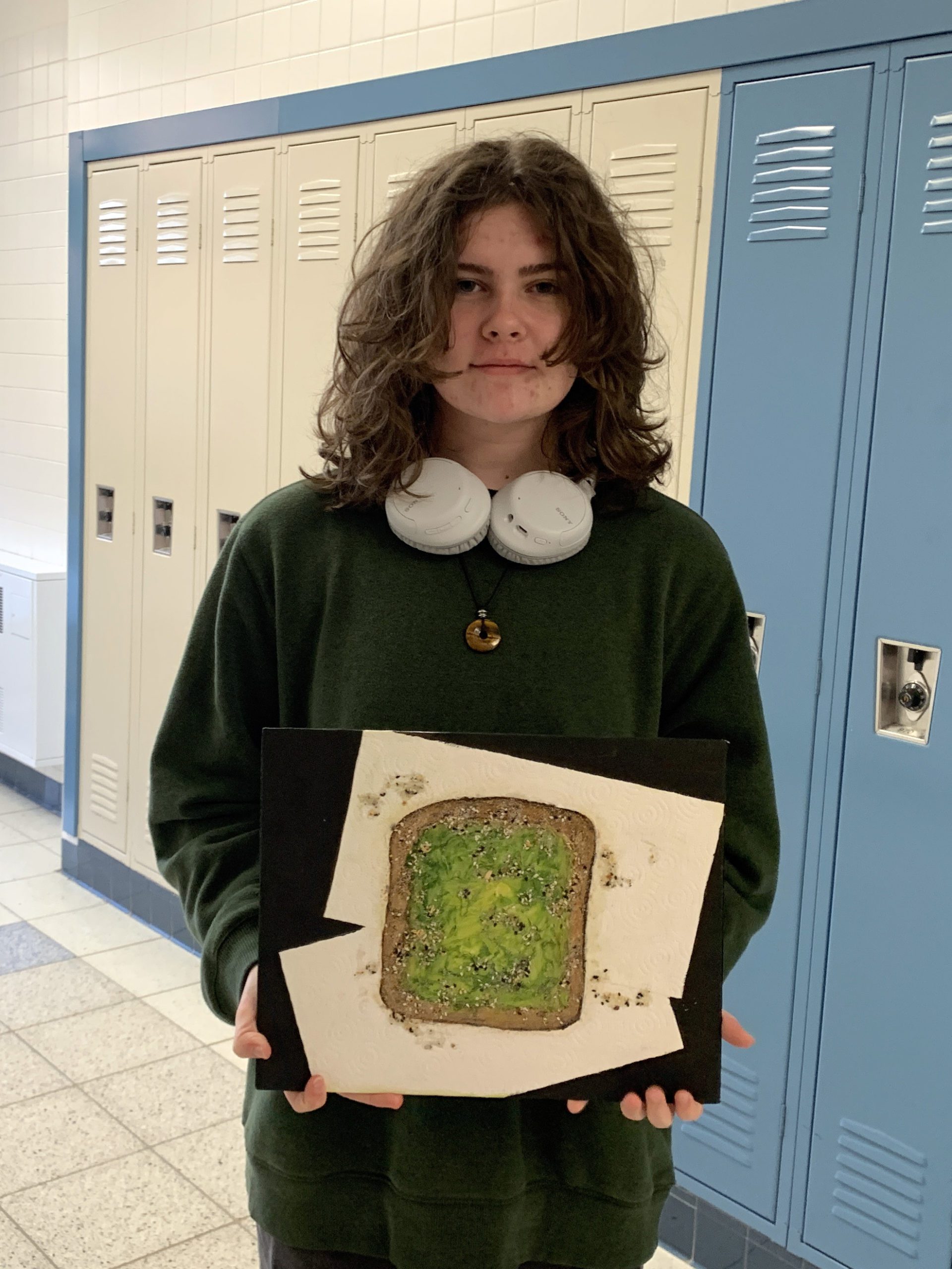 female high school student holding artwork depicting avocado toast
