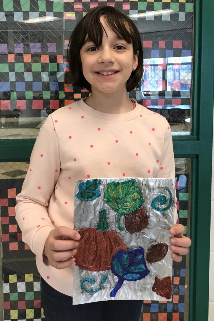 girl holding drawing of fall leaves