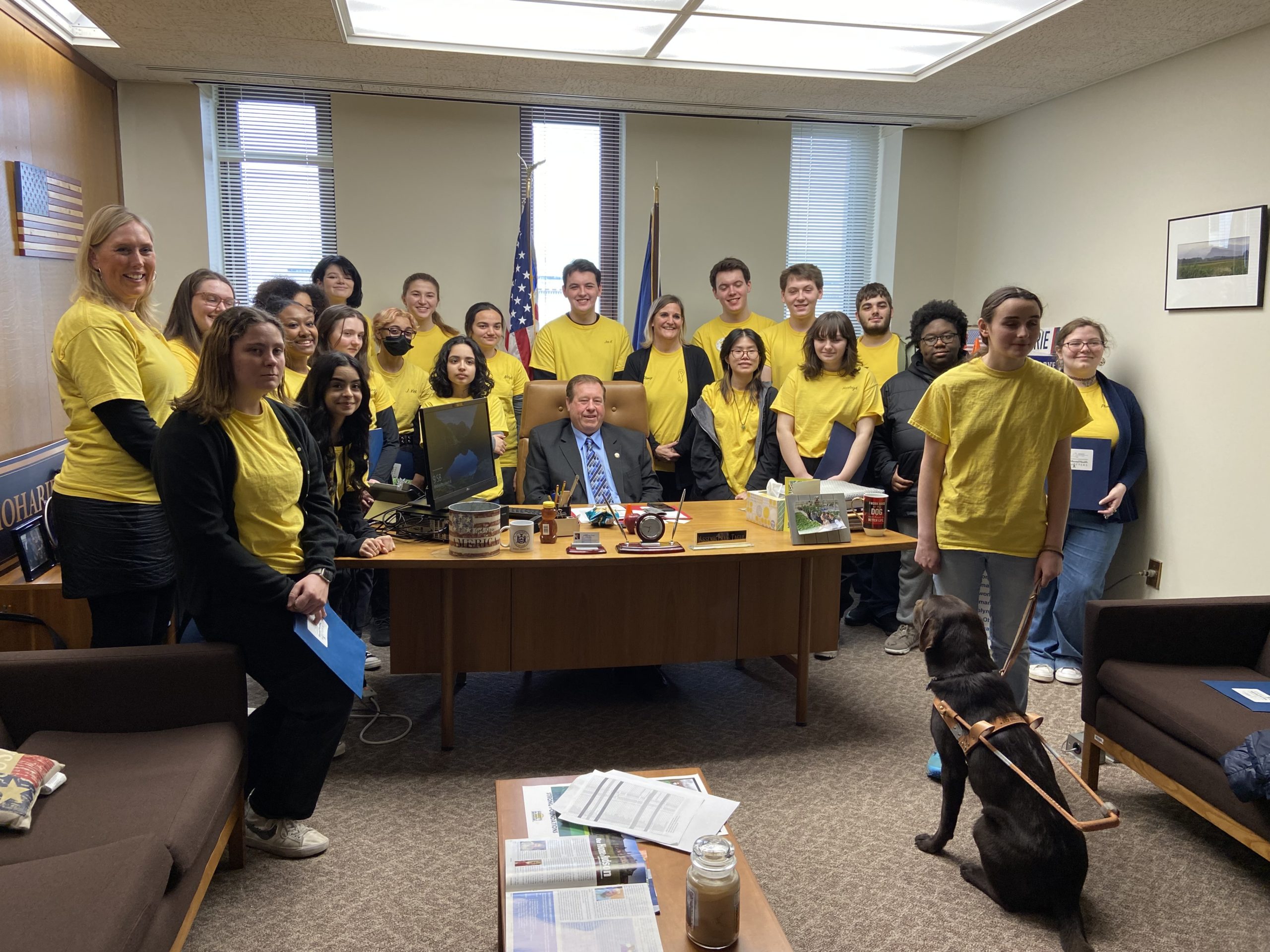 students in yellow shirts pose with assemblyman Chris Tague