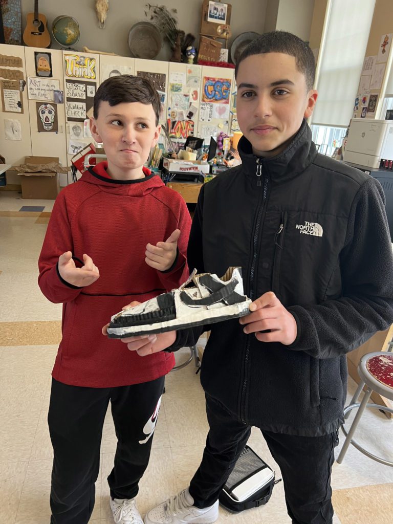 two boys holding ceramic shoe