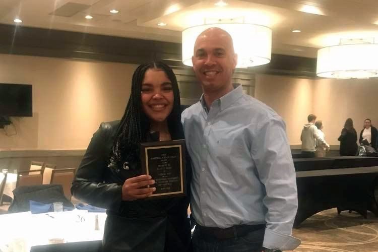 Girl and coach pose with Scholar Athlete plaque.
