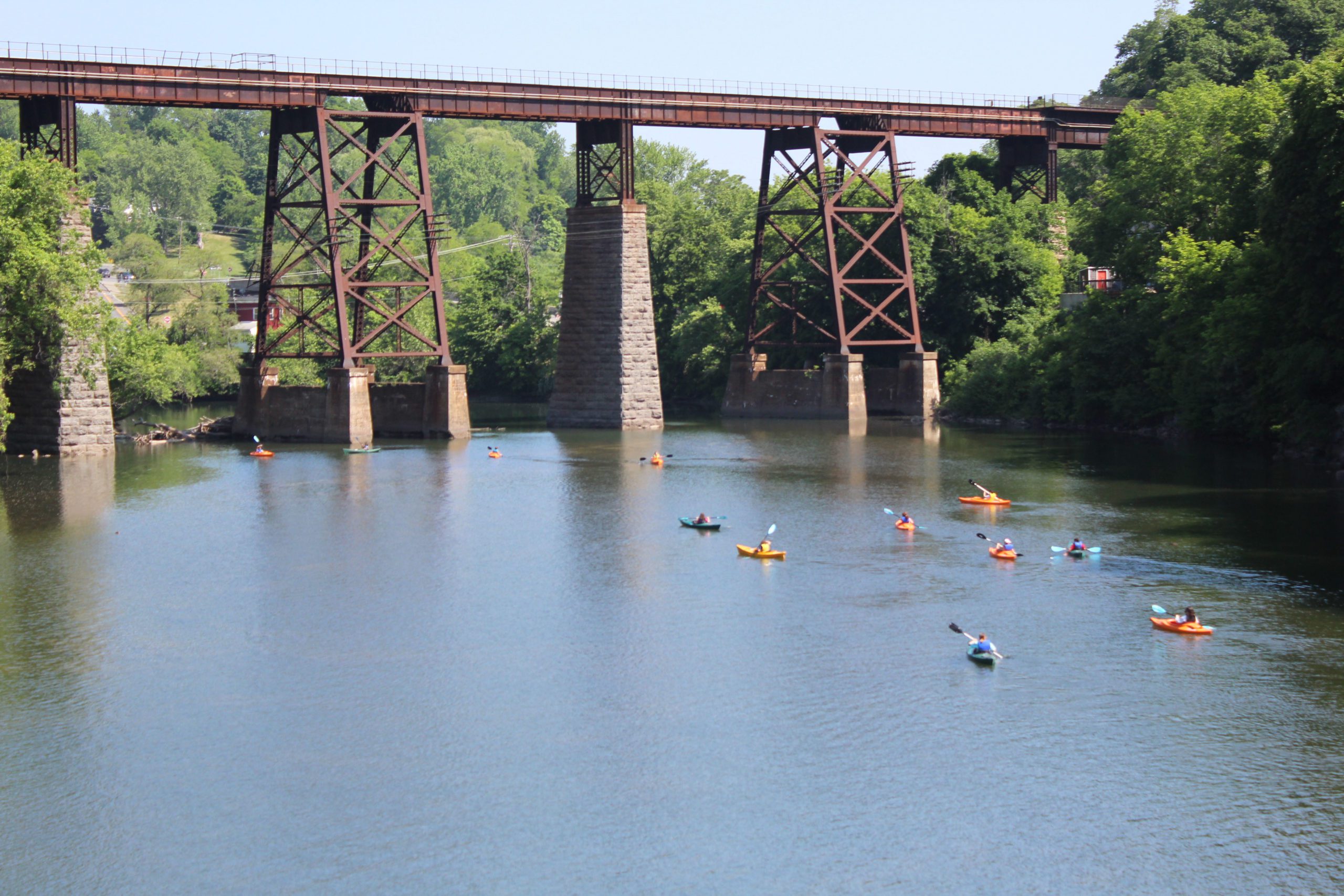 students paddling kayaks up Catskill Creek toward railway bridge