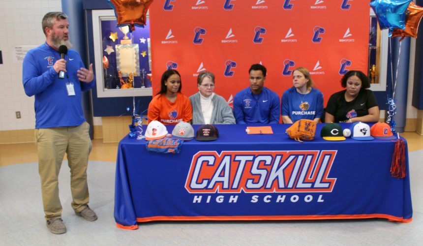Catskill Athletic Director introduced nate and his family sitting at table with Catskil and Purchase sports logos