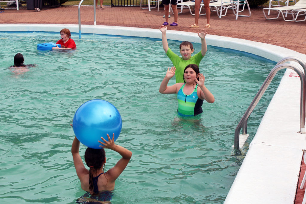 students tossing beach ball in pool
