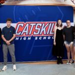 two boys and three girls of high school age standing next yo Catskill High School banner.