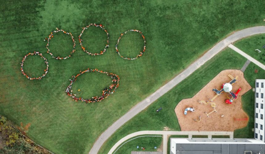 aerial photo of students standing in the shape of a paw print.