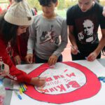 students signing red ribbon banner