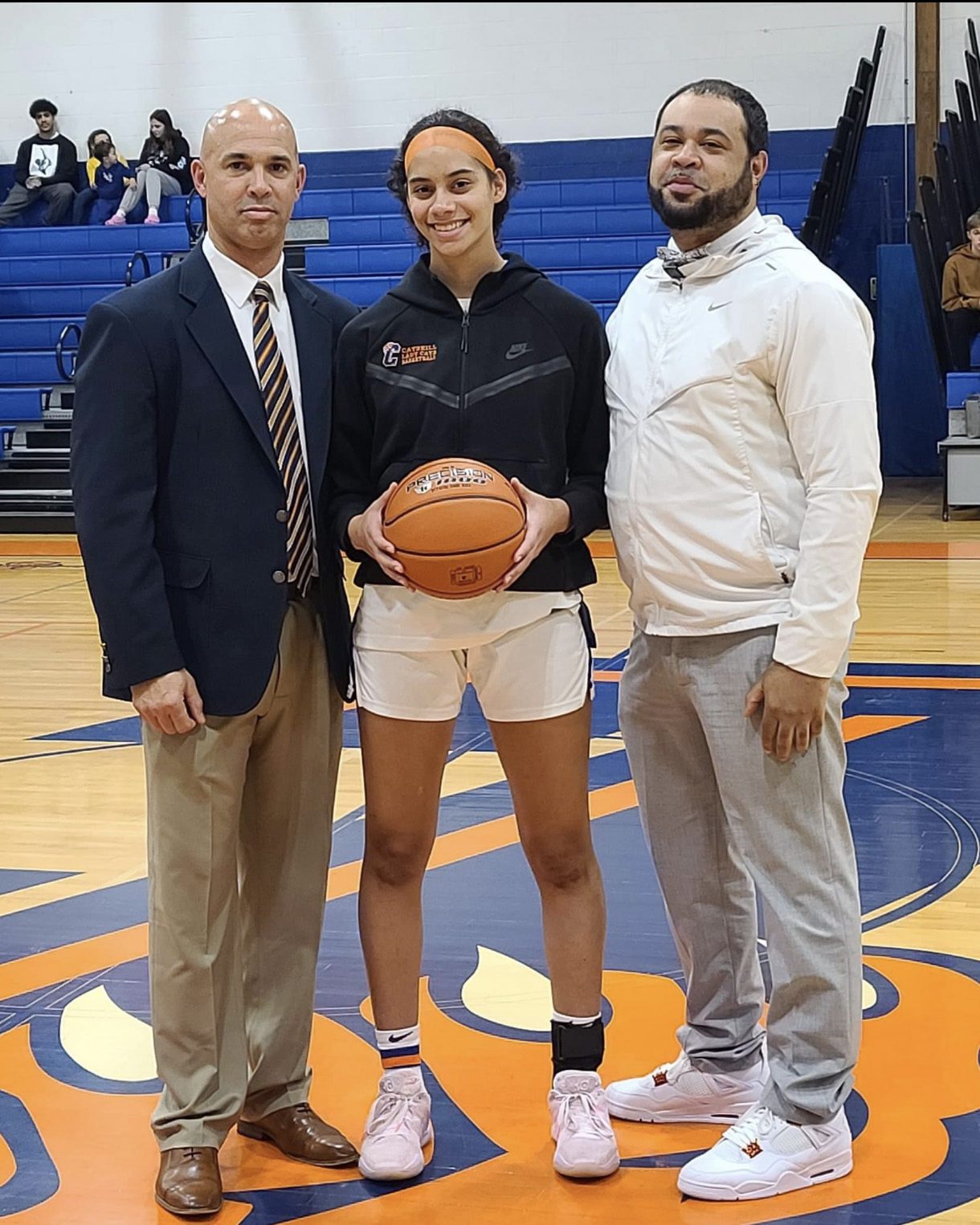 Janay Brantley holding basketball with flanked by Catskill Coaches
