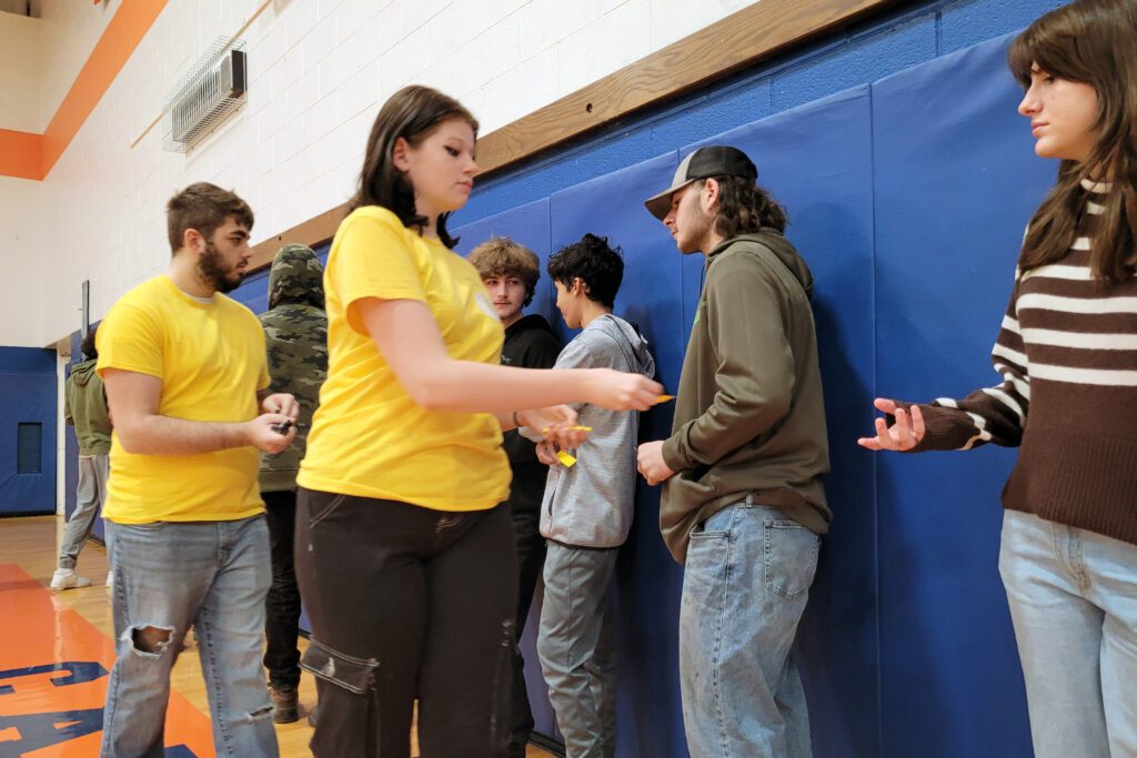 students in yellow shirts handing cards to students