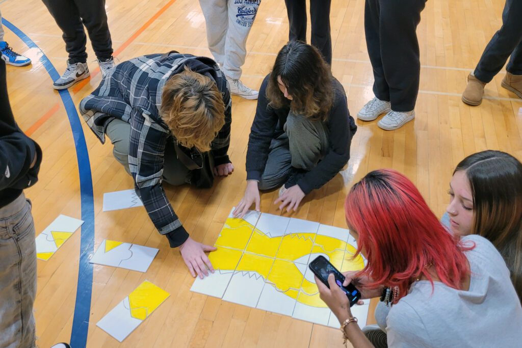 student putting together yellow ribbon puzzle on floor