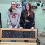 two girls pose with fixed up bench