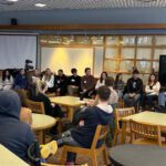 Class of 2023 alumni panel seated in CHS library in front of audience of high school students