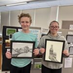 teenage boy and girl holding pencil drawings