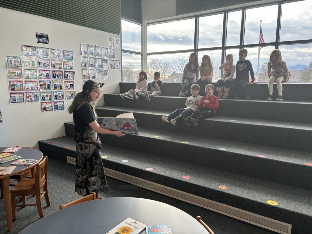 girl reading to young students in library amphitheatre
