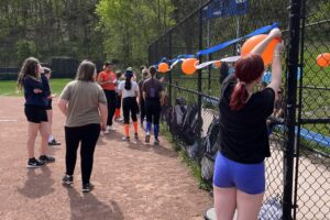 girls putting balloons on backstop