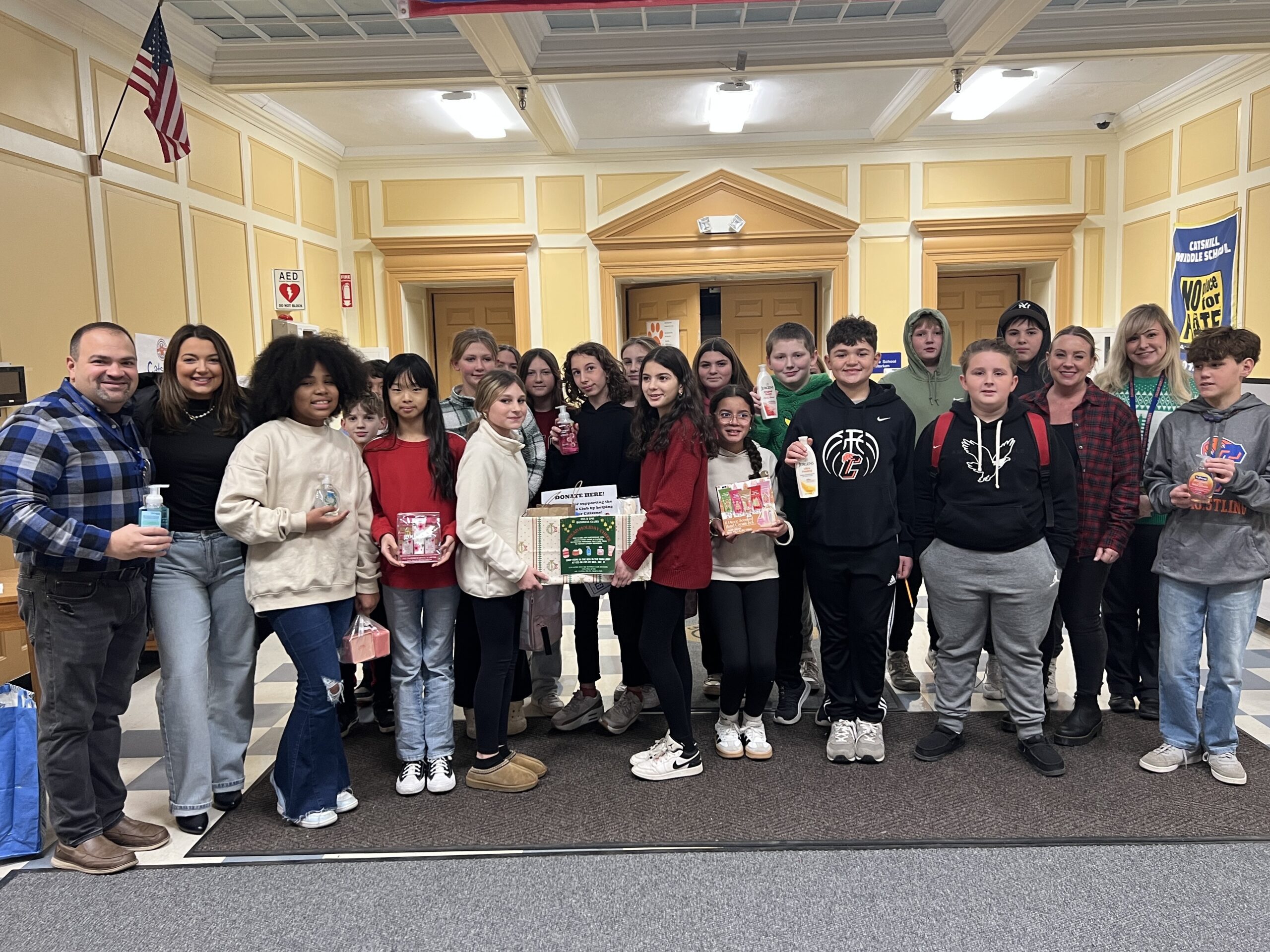 group photo of Catskill Middle School Business Club presenting donation to young woman in CMS atrium.