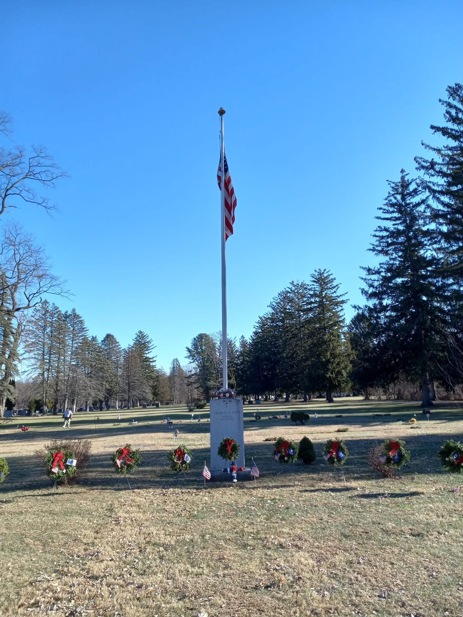 flagpole in cemetery with wreaths below it.