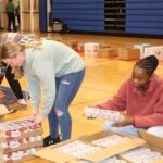 three girls packing boxes of food