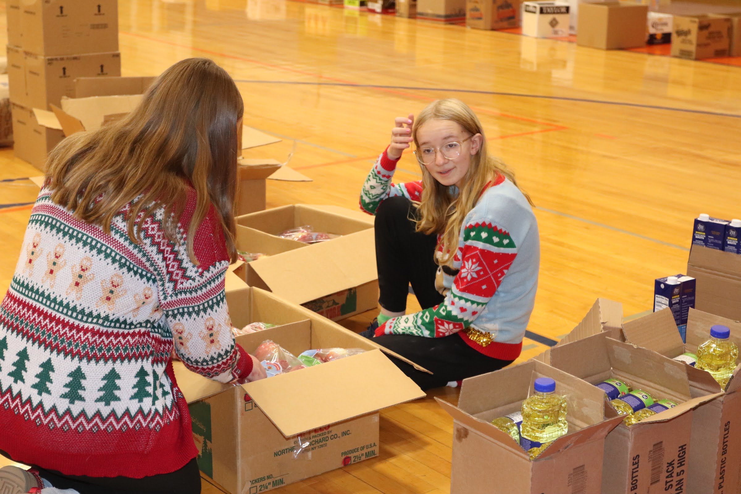 girls packing boxes of food on gym floor