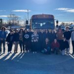 group of students standing in front of bus