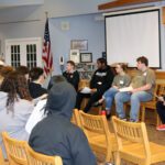 panel of college students seated before audience of high school seniors