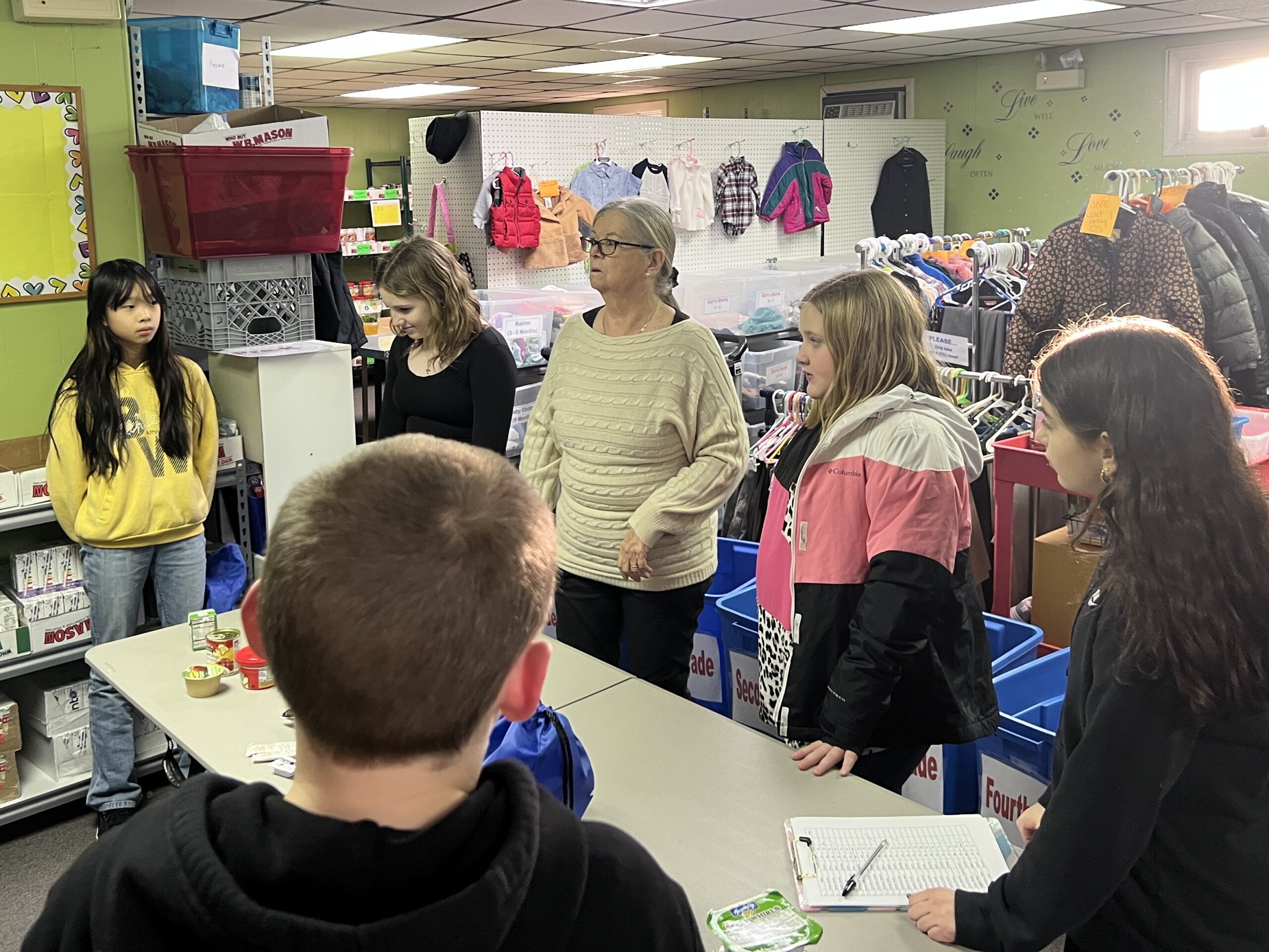 students listening to woman speak at food pantry