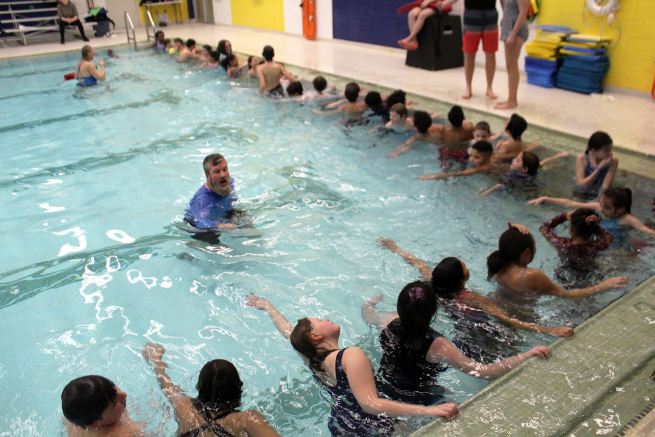 man teaching swimming to kids in pool