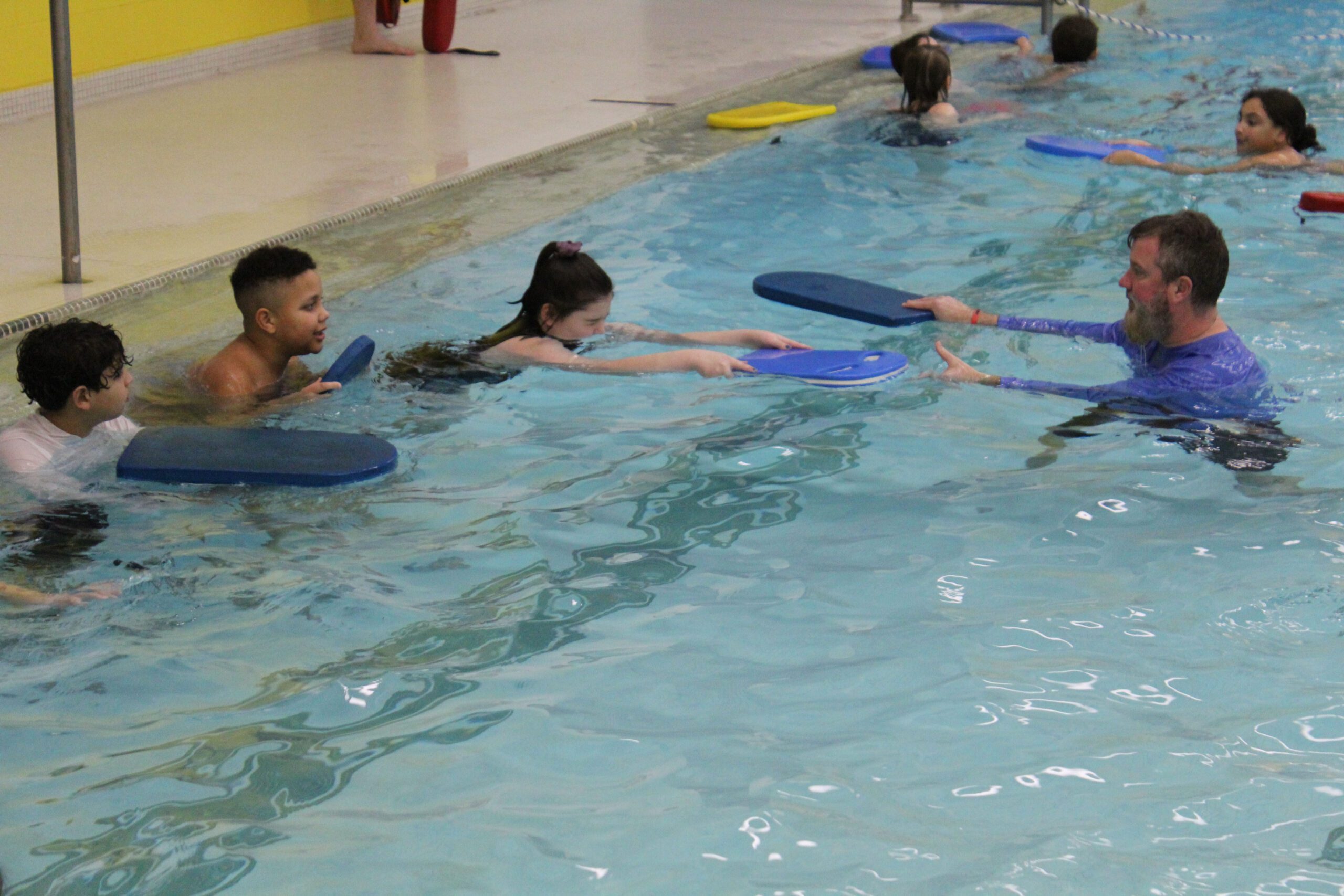 man teaching swimming to kids in pool