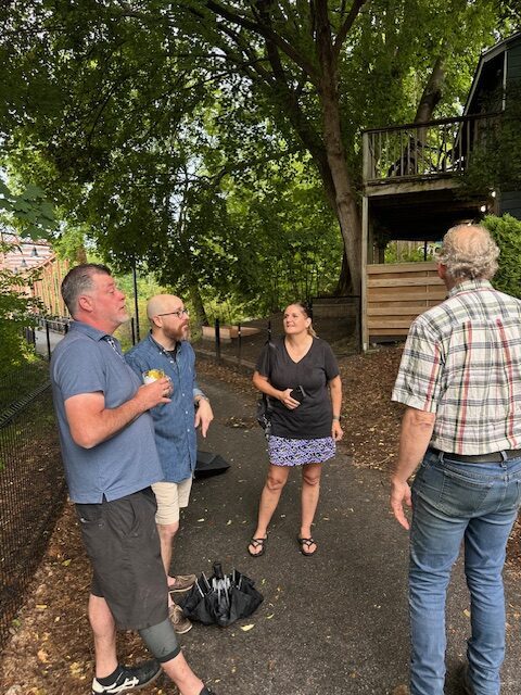 four adults talking to each other next to tiny library