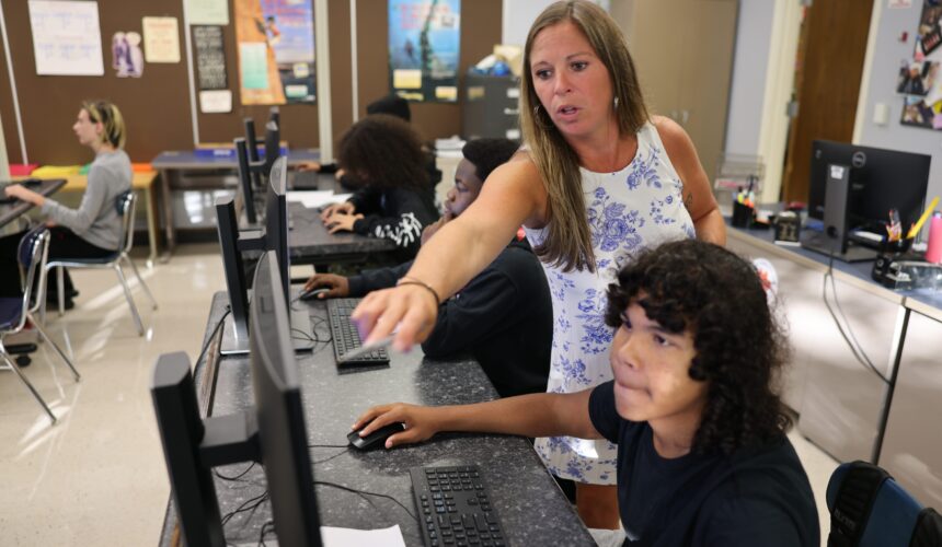 teacher points to computer screen while stunted sits at keypad