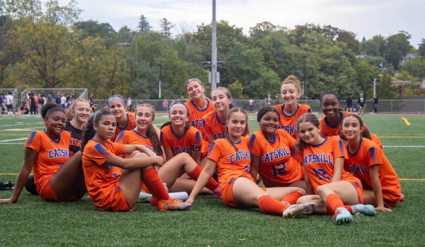 girls soccer team siting on field