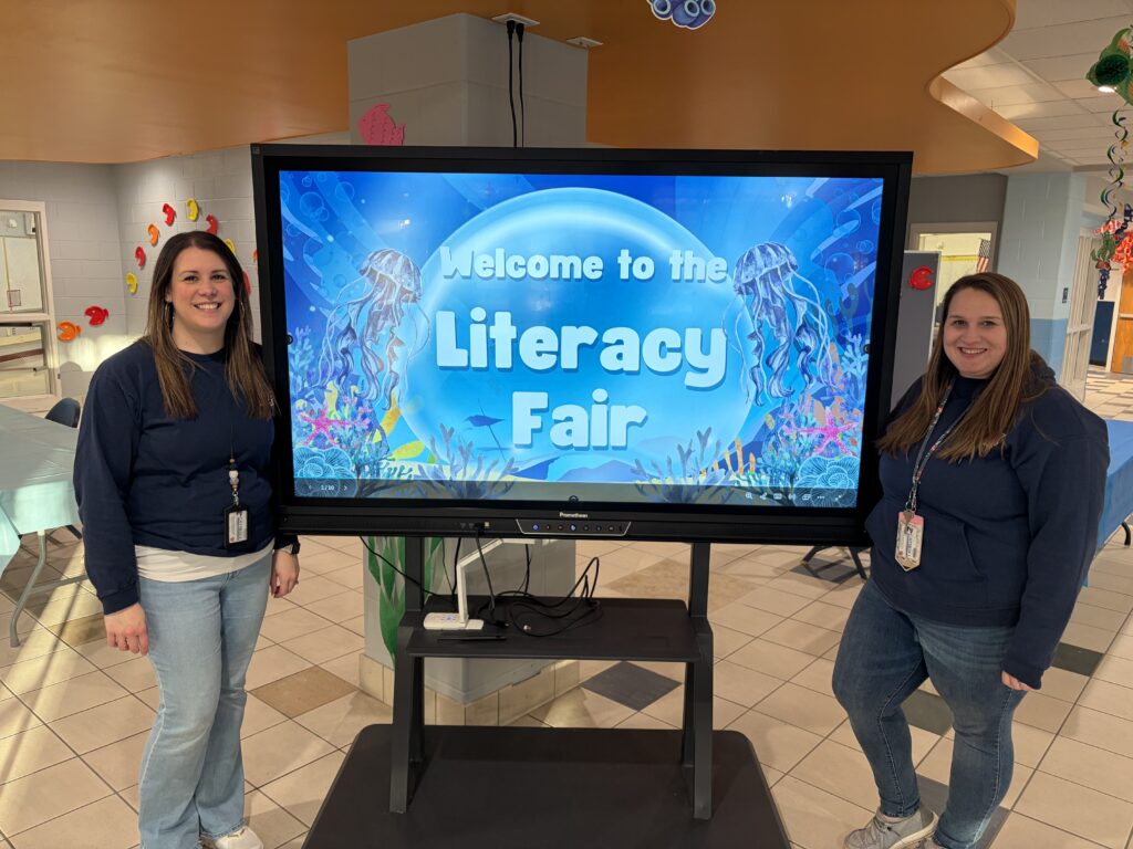 two women pose with literacy fair sign