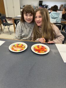 two girls watching Skittles colors mix together
