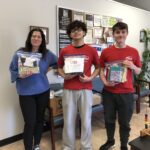 two young men presenting woman with care packages.