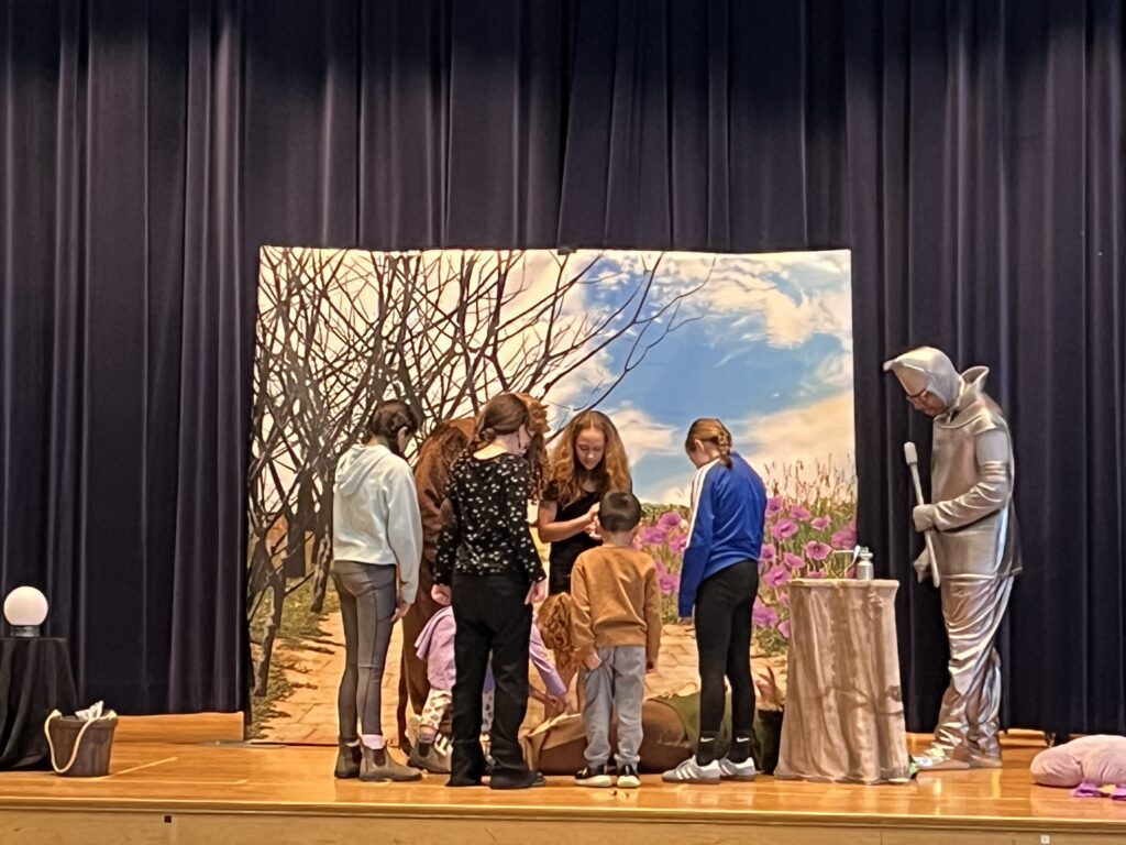 students acting out scene with cast of The Wizard of Oz