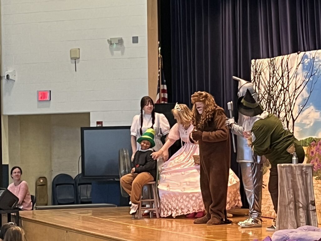 student on stage with cast of The Wizard of Oz