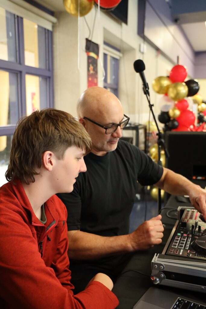 man showing boy how to operate soundboard