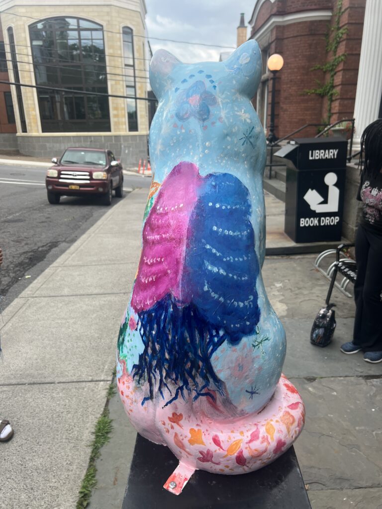 Cat statue with trees and flowers painted on it