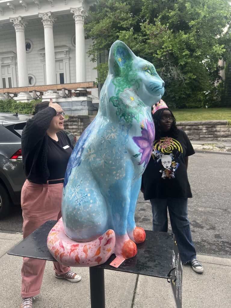 Cat statue with trees and flowers painted on it
