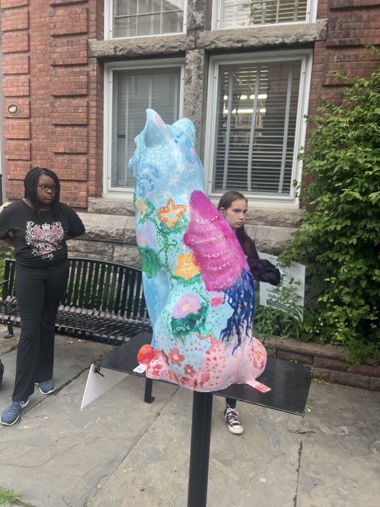 Cat statue with trees and flowers painted on it