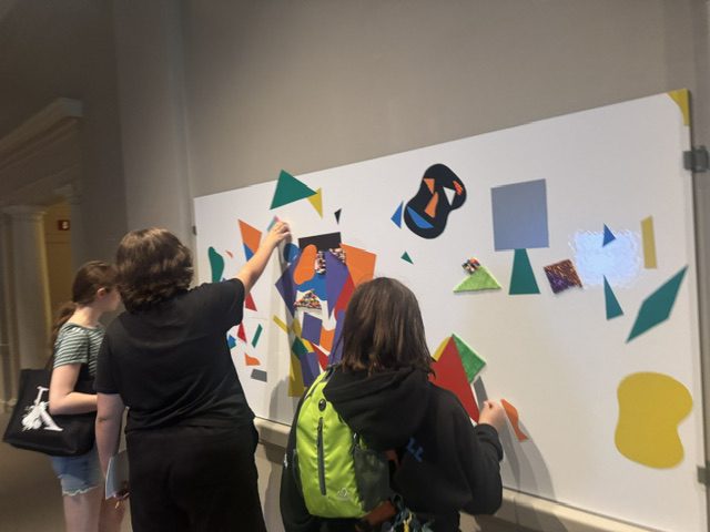 Students using interactive shape on wall to make abstract art