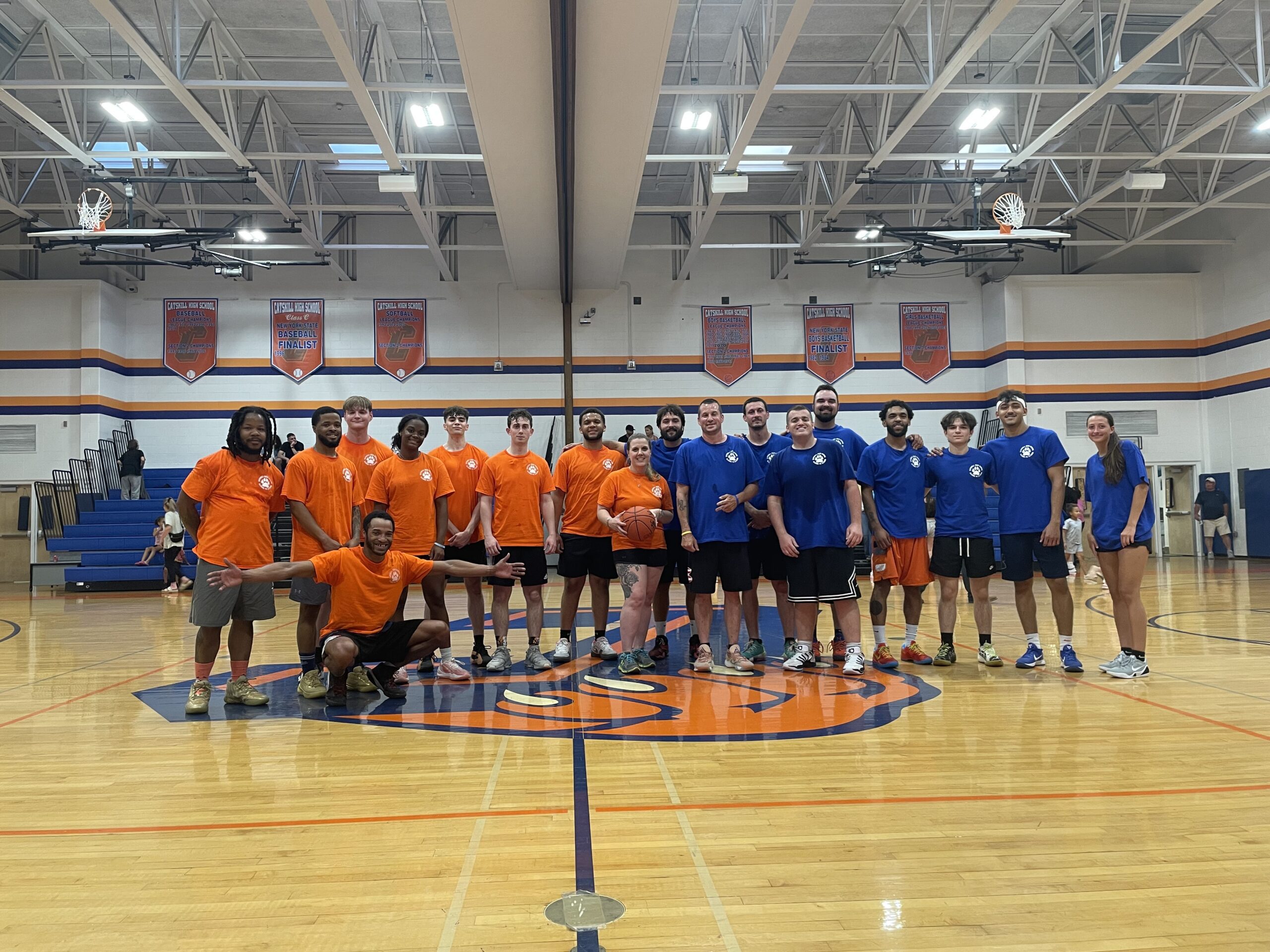 orange and blu alumni teams pose for group photo in gym