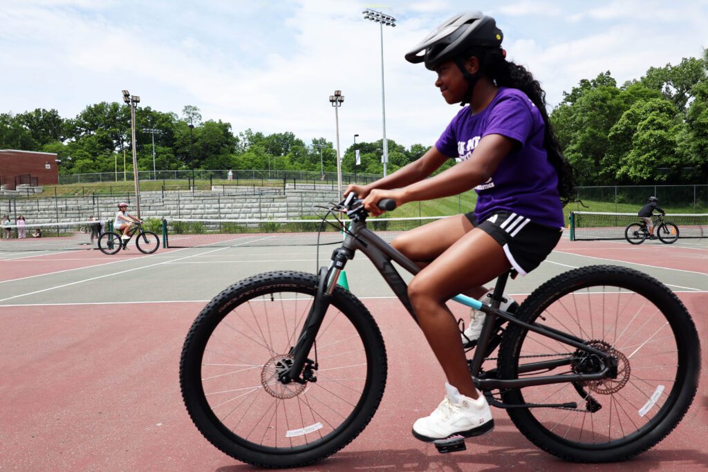 girl riding mountain bikes on tennis court